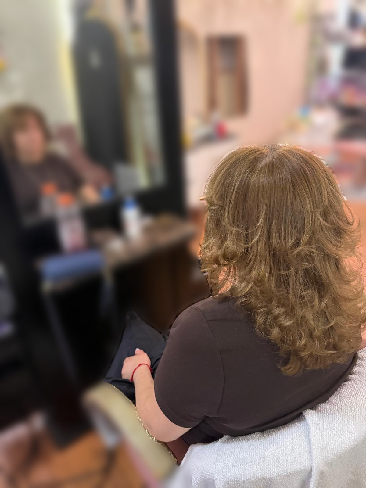 Layered golden brown hair with soft curled ends, seen from behind